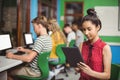 Schoolgirl using digital tablet while other students studying on computer in classroom Royalty Free Stock Photo