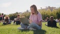 Schoolgirl using laptop while sitting on green grass of campus lawn. Royalty Free Stock Photo