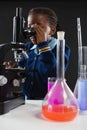 Schoolgirl using microscope against black background Royalty Free Stock Photo