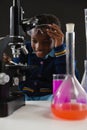 Schoolgirl using microscope against black background Royalty Free Stock Photo