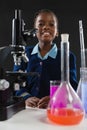 Schoolgirl using microscope against black background Royalty Free Stock Photo