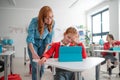 Schoolgirl using tablet with help of teacher during class at school. Royalty Free Stock Photo