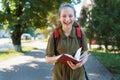 a schoolgirl walks down a city street and reads a book, a bright summer day, back to school concept