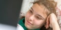 Schoolgirl watches movie on notebook lying in bed closeup