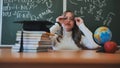 A schoolgirl wearing glasses poses against a background of books, an apple, a globe and a graduation cap. Royalty Free Stock Photo