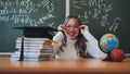 A schoolgirl wearing glasses poses against a background of books, an apple, a globe and a graduation cap. Royalty Free Stock Photo