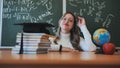 A schoolgirl wearing glasses poses against a background of books, an apple, a globe and a graduation cap. Royalty Free Stock Photo