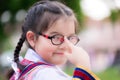 Schoolgirl wearing young girl\'s uniform. Child uses the index finger to push the glasses she is wearing. Sweet smile. Royalty Free Stock Photo