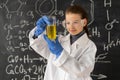 schoolgirl in white coat doing experiments with liquid in chemistry laboratory, young chemist student with flask Royalty Free Stock Photo