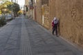 A schoolgirl in white hijab goes to school in the morning. The girl moves very close to the walls of houses