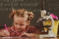 Schoolgirl work on biology research with microscope. Little girl study in biology classroom at school, vintage filter