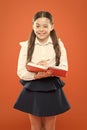 Schoolgirl writing notes on orange background. small girl in school uniform. schoolgirl holding lesson book. get Royalty Free Stock Photo