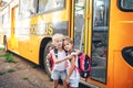 Schoolgirls with backpacks on the background of a school bus, back to school