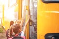 Schoolgirls with backpacks enter the school bus, back to school