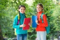 Schoolgirls with backpacks and textbooks in forest, exploring nature concept