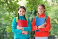 Schoolgirls with backpacks and textbooks in forest, summer camp activity concept