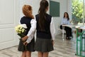 Schoolgirls with bouquet congratulating their pedagogue in classroom. Teacher`s day