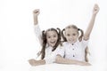 Schoolgirls happy keep hands up while sit at desk white background. Win school quiz. They know right answer. Schoolgirls