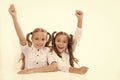 Schoolgirls happy keep hands up while sit at desk white background. Win school quiz. They know right answer. Schoolgirls