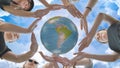 Schoolgirls hug the earth globe with their hands, making a circle out of them on the background of the magic sky. Royalty Free Stock Photo