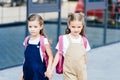 schoolgirls with pink backpacks holding hands