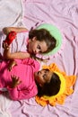 Schoolgirls in pink pajamas lie on colorful pillows, top view