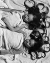 Schoolgirls in pink pajamas sleep on colorful pillows, top view. Girls on white and pink bed sheets background