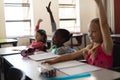 Schoolgirls raising hand in classroom of elementary school