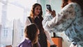 Schoolgirls taking photos of themselves on their phones in class. Royalty Free Stock Photo