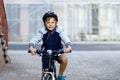 Schoolkid boy in safety helmet riding with bike in the city with backpack. Happy child in colorful clothes biking on