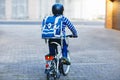 Schoolkid boy in safety helmet riding with bike in the city with backpack. Happy child in colorful clothes biking on