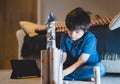 Schoolkid making spaceship for his homework, Happy child boy sitting on the floor playing with rocket toy, Art and craft activity Royalty Free Stock Photo