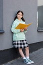 Schoolkid in skirt holding notebook near