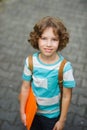 The schoolkid stand on a schoolyard and smiles.