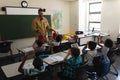 Schoolkids applauding while male Caucasian firefighter teaching about fire safety in classroom