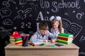 Schoolkids working at the desk with books, school supplies. Left-handed boy writing the text and smiling girl looking at Royalty Free Stock Photo