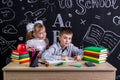 Schoolkids working at the desk with books, school supplies. Left-handed boy writing the text and smiling girl standing Royalty Free Stock Photo