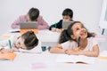 Schoolkids writing in exercise books and using digital tablets in classroom Royalty Free Stock Photo