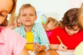 Schoolmates sit together in classroom and write