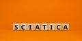 Sciatica symbol. Wooden cubes with word `sciatica`. Beautiful orange background. Medical and sciatica concept. Copy space Royalty Free Stock Photo
