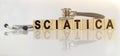 SCIATICA the word on wooden cubes, cubes stand on a reflective white surface, on cubes - a stethoscope Royalty Free Stock Photo