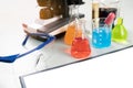 Science lecture clipboard with chemical experiment in school laboratory with beakers, microscope for testing. Royalty Free Stock Photo