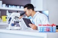 Science, microscope and man on tablet in laboratory for research, test and sample analysis. Digital tech, biotechnology