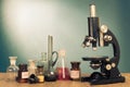 Science. Old vintage microscope and laboratory glass bottles on table front gradient mint blue background. Retro Royalty Free Stock Photo