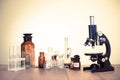 Science. Old vintage microscope and laboratory glass bottles on the table. Retro Royalty Free Stock Photo