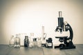 Science. Old vintage microscope and laboratory glass bottles on the table. Retro style sepia photo Royalty Free Stock Photo