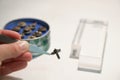 Scientific hand holding a tweezers with a scanning electron microscope sample on a specimen mount