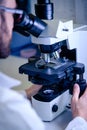 Scientific handling a light microscope examines a laboratory sample for pharmaceutical bioscience research. Concept of science,