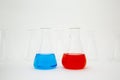 Scientific laboratory glass erlenmeyer flask filled with blue and red liquid with glassware equipment on white background Royalty Free Stock Photo