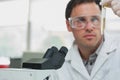 Scientific researcher looking at test tube while using microscope in lab